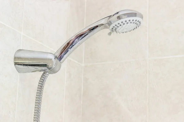 Shower head in holder on wall with beige tiles closeup — Stock Photo, Image