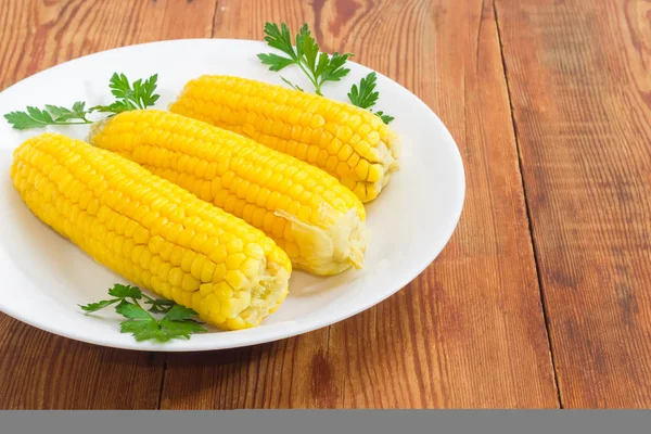 Boiled sweet corn on white dish on wooden surface closeup — Stock Photo, Image