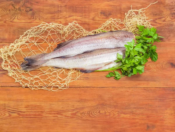 Carcaças não cozidas de pescada numa superfície de madeira — Fotografia de Stock