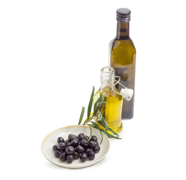 Aceitunas negras, dos botellas de aceite de oliva y rama de olivo — Foto de Stock