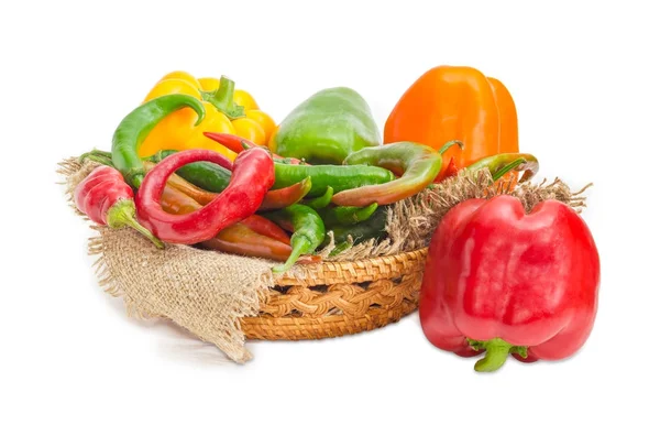 Multi-colored bell peppers and chili in wicker basket — Stock Photo, Image