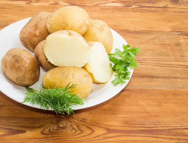 Patatas hervidas en sus pieles y hierbas en primer plano plato —  Fotos de Stock