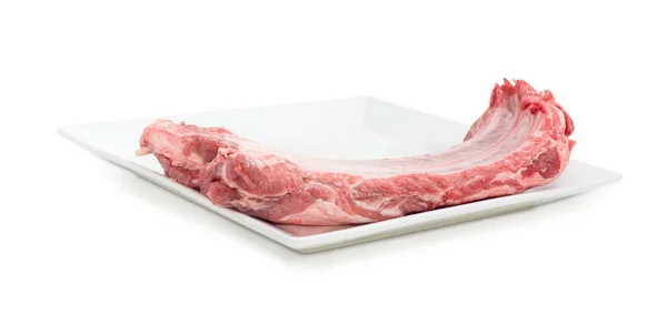 Uncooked pork ribs on a big white dish — Stock Photo, Image