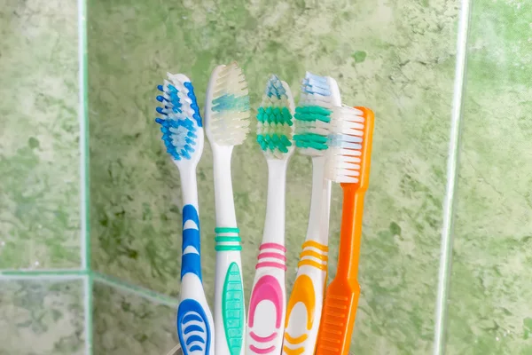 Several toothbrushes on a background of green tile — Stock Photo, Image