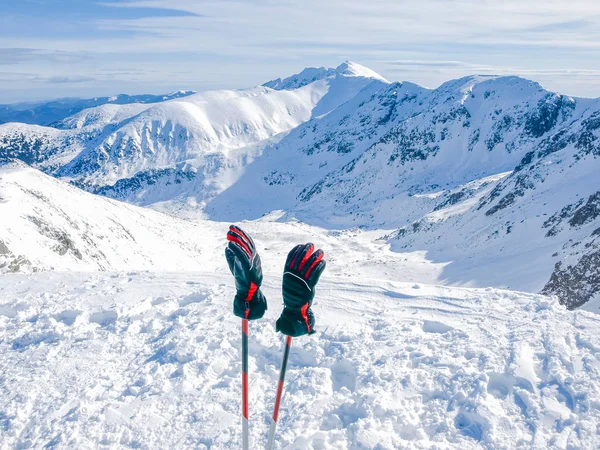 Montanhas de inverno e luvas de esqui em pólos de esqui em primeiro plano — Fotografia de Stock