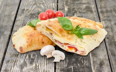 Pişmiş calzone, ham mantar, domates ahşap yüzey üzerinde