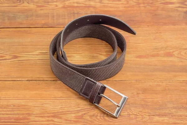 Brown stretch belt on an old wooden surface — Stock Photo, Image