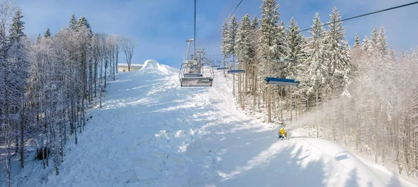 Chairlift and ski piste during preparation in forest