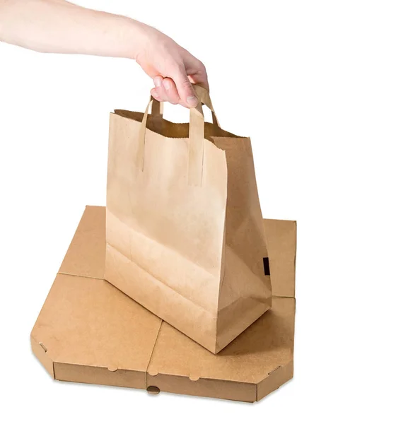 Saco de papel para entrega de alimentos na mão sobre a caixa de pizza — Fotografia de Stock