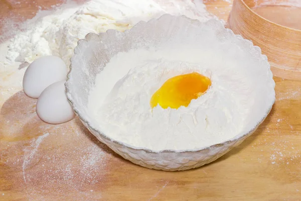 Розбите яйце в мисці з борошном і двома цілими яйцями — стокове фото
