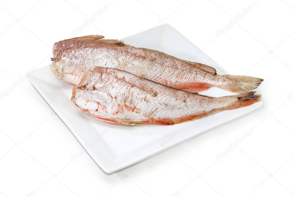 Two carcasses of uncooked red cod on white dish