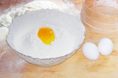 Kırık yumurta un ve iki tam yumurta bir kase içinde 