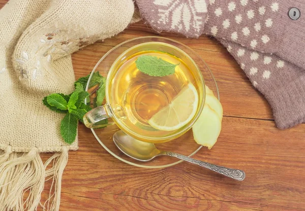 Чай с лимоном, мятой, имбирем рядом с шерстяными варежками, шарф — стоковое фото