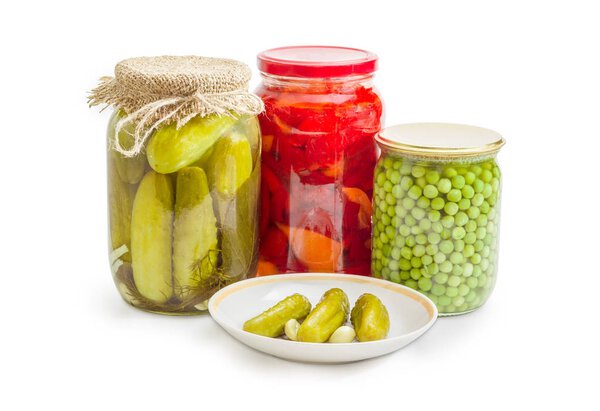 Canned cucumbers on saucer against of canned vegetables in jars