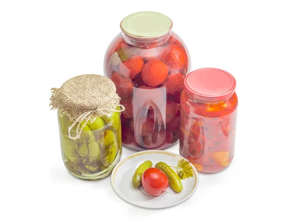 Pepinos enlatados y tomate en platillo, frascos de verduras enlatadas — Foto de Stock