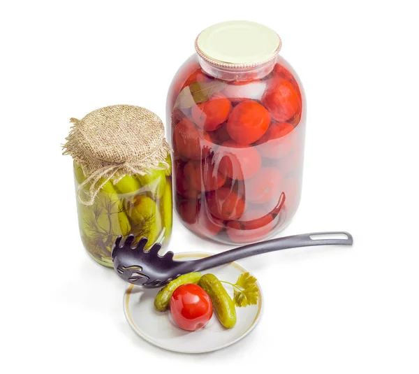 Dois frascos e pires diferentes com pepinos e tomates enlatados — Fotografia de Stock