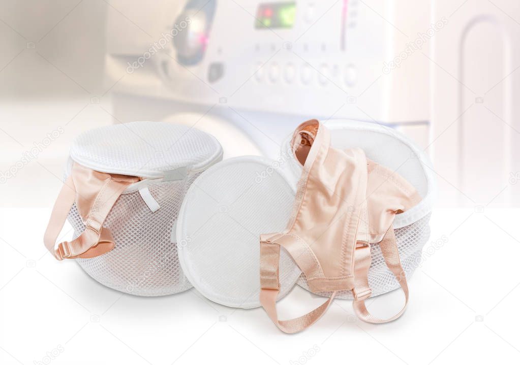 Two laundry bags bras on blurred background of washing machine