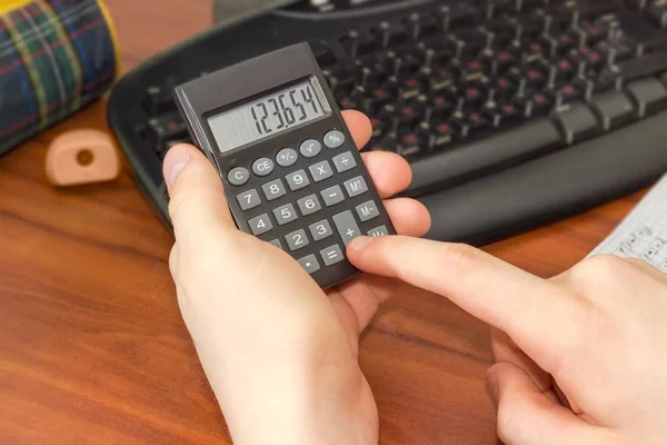 Kalkulator elektroniczny w ręku uczniak na pulpicie — Zdjęcie stockowe