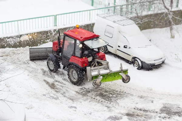 小拖拉机雪犁在庭院工作期间在降雪 — 图库照片