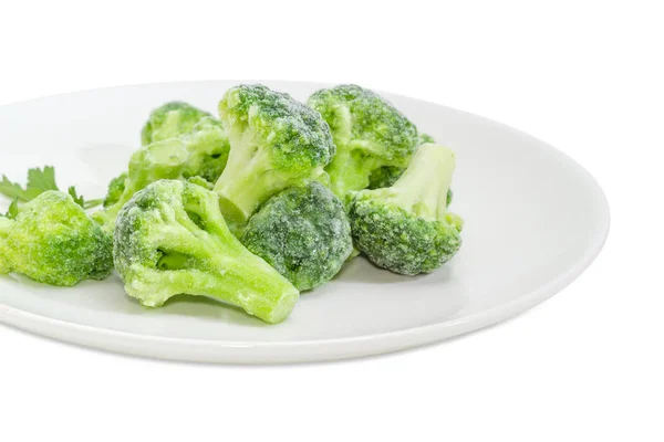 Frozen broccoli on dish closeup on a white background — Stock Photo, Image