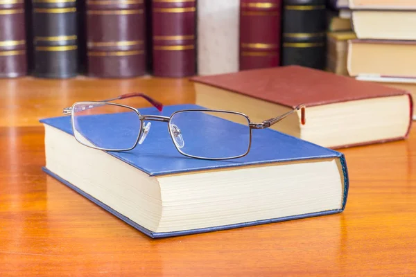 Brille auf dem geschlossenen Buch gegen andere Bücher Nahaufnahme — Stockfoto