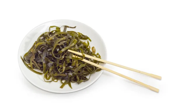 Salada de algas marinadas em prato branco com pauzinhos de bambu — Fotografia de Stock