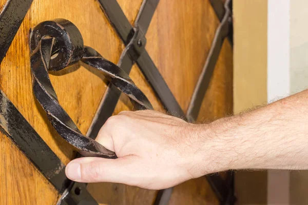 Menschliche Hand hält die eiserne Türklinke des Klosters — Stockfoto