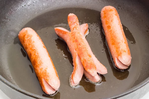 Венские сосиски на сковородке во время жарки крупным планом — стоковое фото