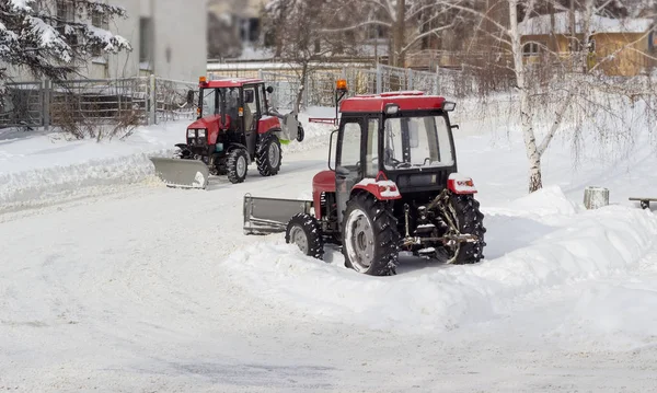 Twee verschillende kleine rode trekker sneeuw plows tijdens werk — Stockfoto