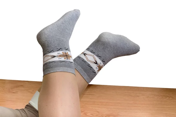 Frauenbeine in wollenen Thermosocken auf einem Holzboden — Stockfoto