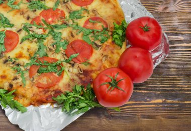 Pişmiş pizza ve bir folyo üzerinde taze domates parçası 