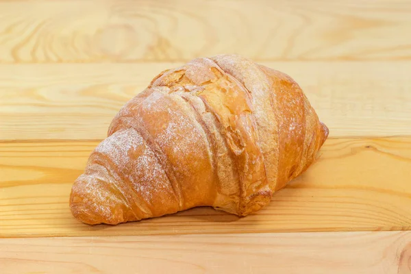 Croissant al horno en una mesa de madera de color claro — Foto de Stock