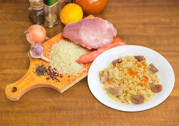 Pilaf gătit și ingrediente pentru prepararea sa pe masa de gătit — Fotografie, imagine de stoc