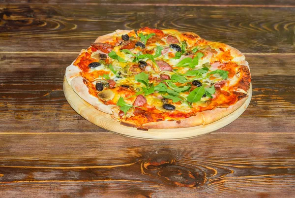 Ahşap pizza kesme tahtası üzerinde eski tablo üzerinde pişmiş pizza — Stok fotoğraf