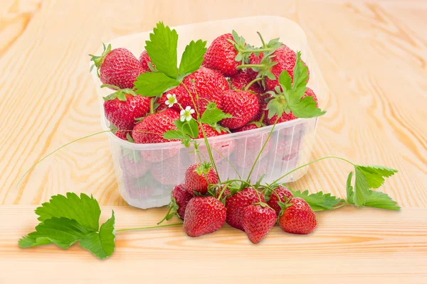 Fresas en recipiente y junto a él en la superficie de madera —  Fotos de Stock