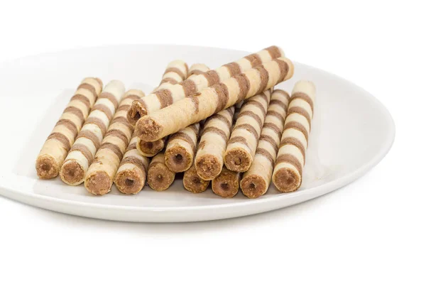 Tubolari di wafer a strisce con crema al cioccolato su primo piano piatto bianco — Foto Stock