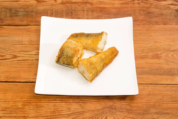 Три ломтика жареной рыбы на тарелке — стоковое фото