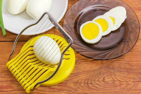 Egg slicer and boiled eggs on an old rustic table