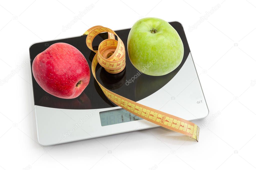 Apples and tapeline on kitchen scales, concept of excess weight