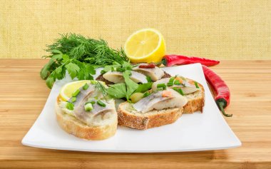 Salamura ringa balığı filetosu kare tabak üzerinde çeşitli açık sandviçle