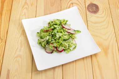 Bahar salatası beyaz tabak üzerine dilimlenmiş taze sebze