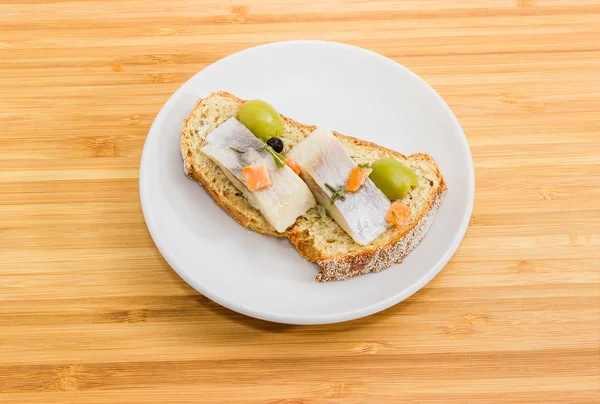 Nyitott szendvics pácolt heringet, az olajbogyó és a barna csírázott kenyér — Stock Fotó