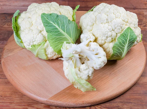 Fresh cauliflower on the wooden serving board on rustic table — Stock Photo, Image