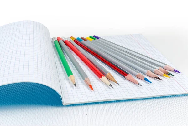 Verschiedene scharfe Bleistifte auf dem offenen Schulheft ausgelegt — Stockfoto