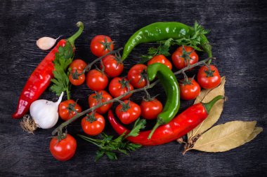 Siyah yüzeydeki çeşitli sebzelerin, yeşilliklerin, baharatların üst görüntüsü 