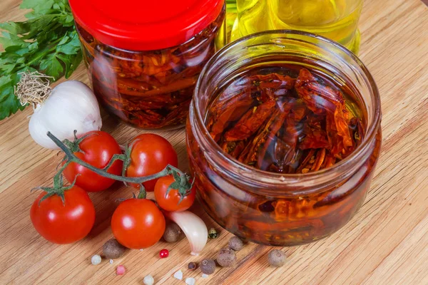 Dried tomatoes in olive oil in jars among ingredients close-up — Stock Photo, Image