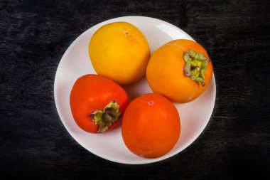 Siyah arkaplanda beyaz tabakta hurma meyvesi, üst görünüm