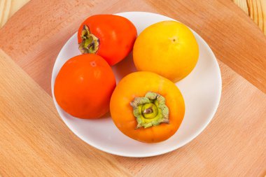 Ahşap yüzeyde beyaz tabakta farklı meyveler.