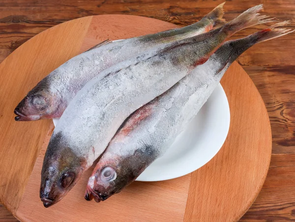 Pescado Redbait congelado en el plato en el tablero de servir de madera —  Fotos de Stock