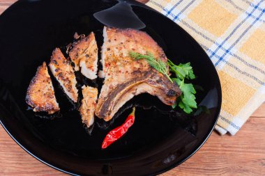 Kızarmış domuz filetosu. Tabakta kemik kırıntısı, kısmen kesilmiş. 